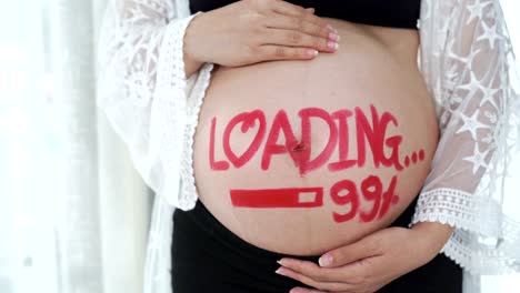 panning-shot-of-pregnant-woman-with-loading-99%-concept-painted-on-her-belly