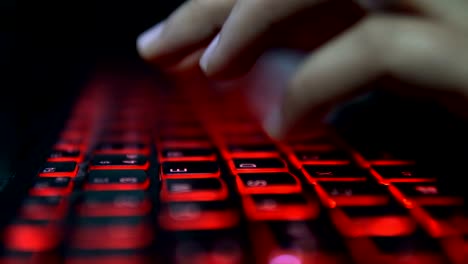 Teenage-Hacker-Girl-greift-Unternehmensserver-in-Dunkelheit-an,-tippen-auf-Red-Lit-Laptop-Keyboard.-Raum-ist-dunkel