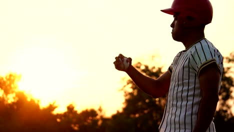 Baseball-Spieler-hält-einen-Baseball-mit-dem-Licht-des-Sonnenuntergangs