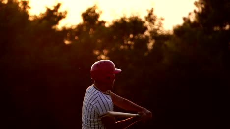 Baseballspieler-hält-einen-Baseballschläger-mit-dem-Licht-des-Sonnenuntergangs