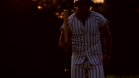 Baseballspieler-hält-einen-Baseballschläger-mit-dem-Licht-des-Sonnenuntergangs