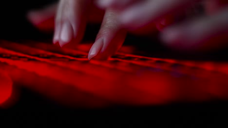 Hacker-Mädchen-Hand-tippen-auf-Tastatur-mit-roter-Hintergrundbeleuchtung