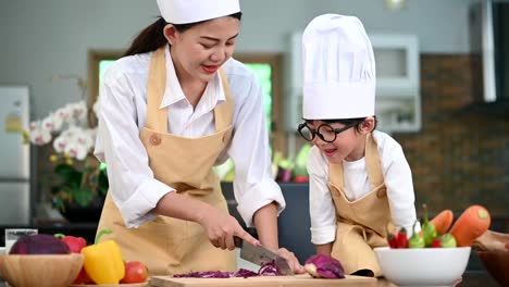 Schöne-asiatische-Frau-und-niedlichen-kleinen-Jungen-mit-Brille-bereiten-sich-auf-das-Kochen-in-der-Küche-zu-Hause-zusammen.-Lebensstil-und-Familie.-Hausgemachte-Speisen-und-Zutaten.-Zwei-Personen,-die-Ketogenic-DiätSalat-machen