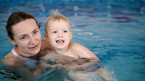 Schwimmbad.-Mama-bringt-einem-kleinen-Kind-das-Schwimmen-im-Pool-bei.