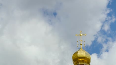 Die-goldene-Kuppel-der-eine-orthodoxe-Kirche-auf-dem-Hintergrund-des-blauen-Himmels-und-der-Wolken.-Goldenes-Kreuz-auf-der-Kuppel-des-Tempels.-Zeitraffer.-Ein-geloopten-Clip-ohne-Pausen.-4K-Ultra-HD,-UHD