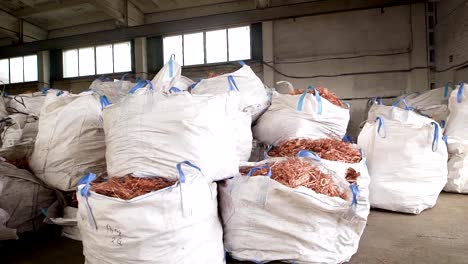 huge-white-bags-with-copper-scrap-from-wires-are-lying-in-a-warehouse-of-scrap-metal-processing-plant