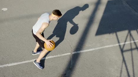 Joven-jugador-de-baloncesto-de-caucásico-botando-una-pelota-en-el-estadio,-el-deporte-y-hobby