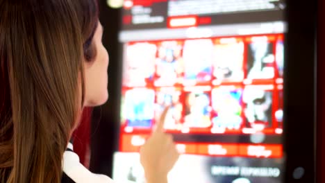 Teenager-buying-movie-ticket-from-vending-machine-at-cinema.-Female-make-gestures-by-touching-screen