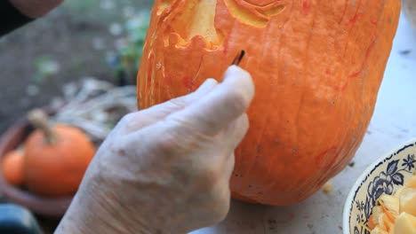 Closeup-man-carves-Halloween-pumpkin