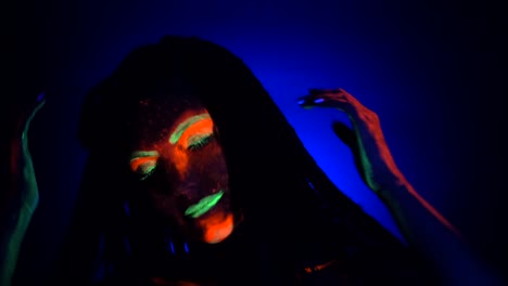 Fashion-model-woman-with-braids-dancing-in-neon-light.-Fluorescent-makeup-glowing-under-UV-black-light.-Night-club,-party,-halloween-psychedelic-concepts