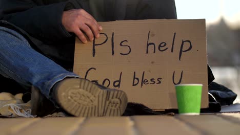 Close-up-beggar-male's-legs-and-cardboard-sign