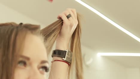 Woman-hairdresser-combing-strand-hair-with-hairbrush-during-cutting-in-beauty-salon.-Close-up-hairdresser-making-female-haircut-in-hairdressing-salon