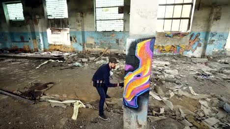 High-angle-shot-of-young-urban-painter-creating-abstract-image-on-column-in-old-damaged-building.-Modern-art,-street-artist,-creativity-and-people-concept.