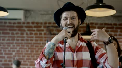 Emotional-bearded-guitarist-singing-into-microphone