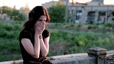 A-view-from-left-to-right-of-a-sad,-bitterly-crying-woman,-standing-on-a-bridge