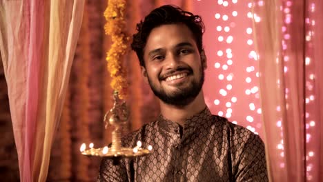 Un-hombre-guapo-con-kurta-sonrisas-en-un-cálido-interior-de-la-casa-decorado-con-luces-y-flores