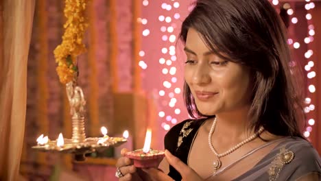 Eine-Nahaufnahme-von-schönen-und-traditionellen-Frau-Beleuchtung-einer-Lampe-während-Diwali-fest.