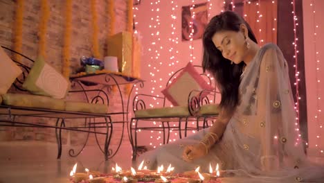 An-attractive-and-smiling-woman-sitting-on-the-floor-in-a-traditional-sari-and-drawing-a-Rangoli