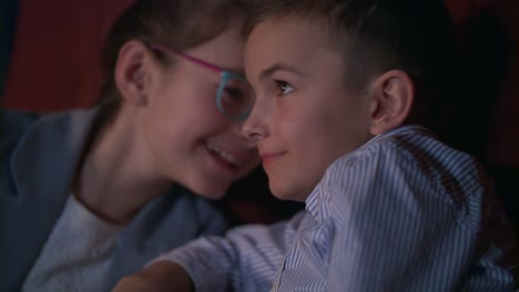 Girl-whispering-to-boy-watching-movie-in-cinema.-Child-movie-entertainment