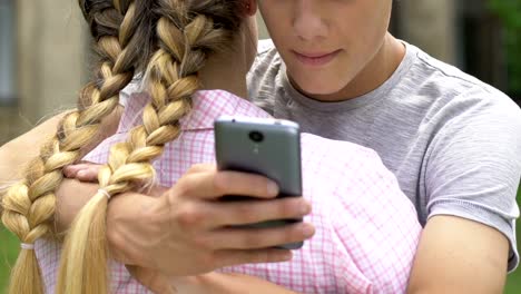 Boy-texting-on-smartphone-while-embracing-girlfriend,-lie-and-betrayal,-closeup