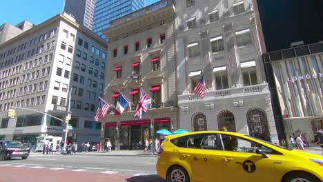 5th-Avenue-shopping-and-St-Patricks-Cathedral-with-traffic-passing-by-in-New-York-City,-Manhattan,-New-York