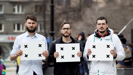 Junge-Erwachsene-kaukasischen-Menschen-blicken-in-die-Kamera-bei-Demonstration.-Schwere-Jungs