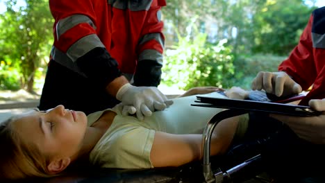 Male-paramedic-doing-indirect-heart-massage,-colleague-using-tablet-for-records