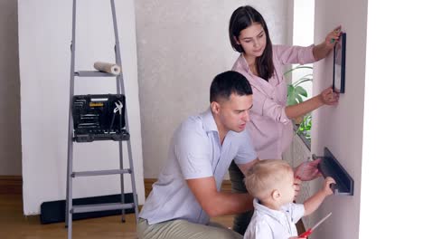 padre-enseña-hijo-a-perno-estante-a-la-pared-con-un-destornillador-mientras-que-reparación-de-apartamento