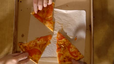 Company-of-three-people-reaches-for-pieces-of-pizza