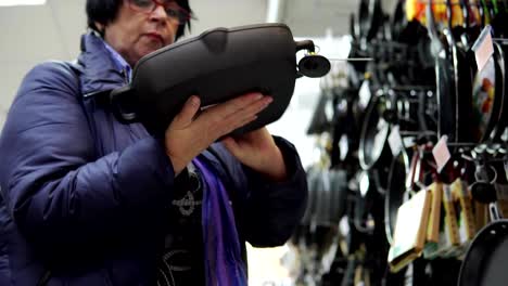 A-mature-woman-chooses-a-cast-iron-frying-pan-in-the-supermarket.