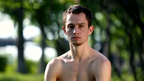 Handsome-bare-chested-man-looking-at-camera-during-yoga-exercises.