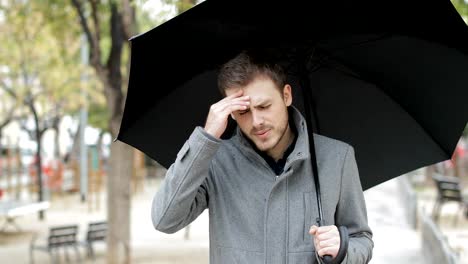 Hombre-que-sufre-de-dolor-de-cabeza-bajo-la-lluvia