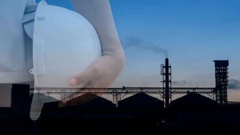 Double-exposure.-Engineer-or-worker-hold-helmet.-Background--factory-industry-Set-of-storage-tanks-raw-material-feed-mills.-Safety-at-work-concept.-Time-Lapse