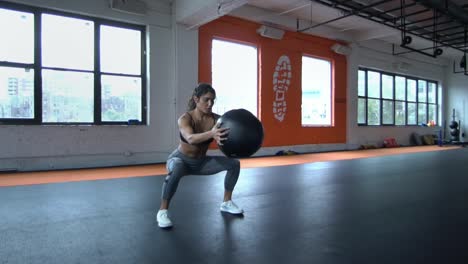 Ajuste-formación-morena-joven-atlético-con-la-bola-de-medicina-en-el-gimnasio-saludable-cuerpo-entrenamiento-de-kickboxing.-Cámara-lenta.