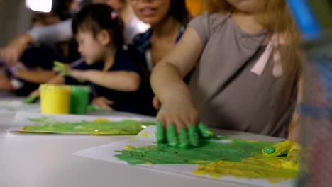 Little-girl-with-hands-in-paint-drawing-on-paper