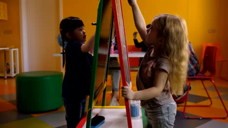 Cute-diverse-girls-drawing-on-easel-board-at-class