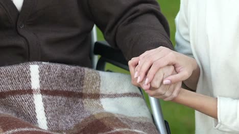 Mujer-de-la-mano-del-paciente-en-silla-de-ruedas,-programa-de-voluntariado,-concepto-de-la-caridad