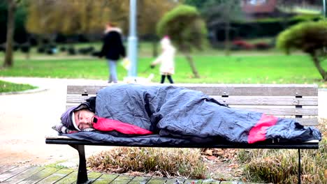 Homeless-man-sleeping-on-bench-at-park