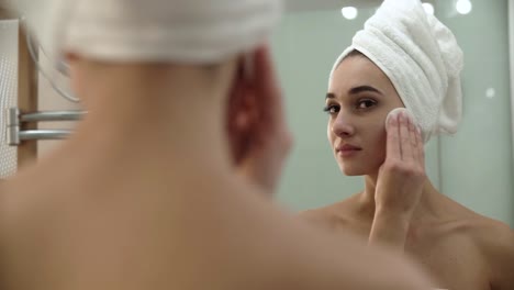 Cuidado-de-la-piel.-Mujer-de-limpieza-de-cara-con-la-loción-en-el-baño