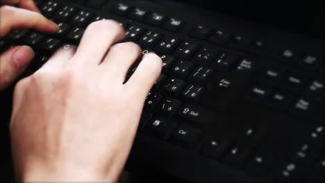 Man-typing-on-keyboard.using-computer-in-the-dark-room.