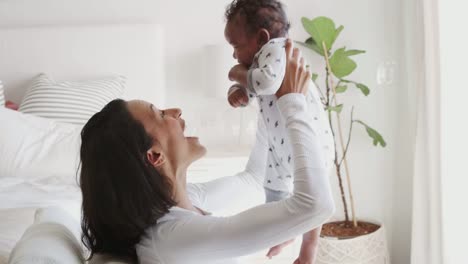 Millennial-mixed-race-mother-lifting-her-baby-and-smiling-to-him