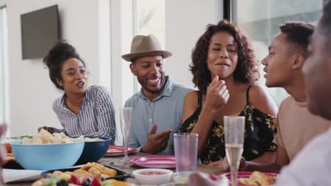 Three-generation-black-family-sitting-together-at-dinner-table-talking-during-a-family-celebration