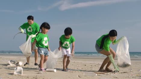 Grupo-de-voluntarios-en-camisetas-verdes-limpiando-la-playa-con-bolsas-de-plástico-llenas-de-basura.-Cámara-lenta.-Concepto-ecológico-seguro.-resolución-4k.