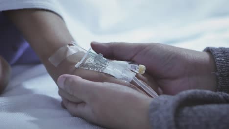 Mother-holding-hand-of-his-son-sick-bed-in-the-hospital.-Touch-the-hand-Slow-motion.-care-encouragement