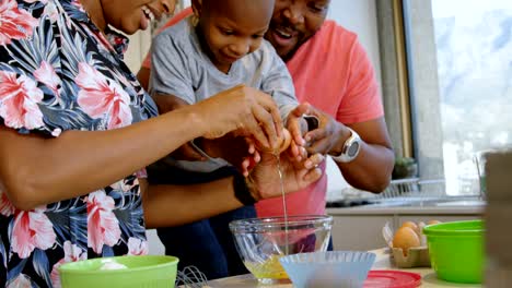 Parents-and-son-cracking-egg-in-kitchen-at-home-4k