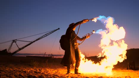 Ein-Mann-mit-einem-Flammenwerfer-bei-Sonnenuntergang-in-Zeitlupe.-Kostüm-für-Zombie-Apokalypse-und-Halloween.