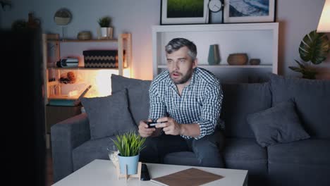 Man-playing-video-game-and-chewing-popcorn-enjoying-leisure-at-night