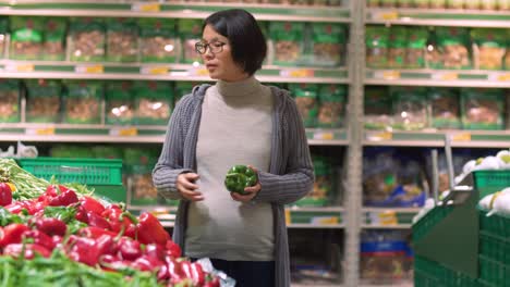 Mujer-asiática-embarazada-comprando-verduras-en-el-mercado