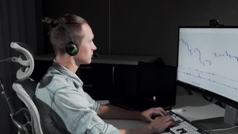 Young-man-using-headset-with-microphone-working-online-late-at-night