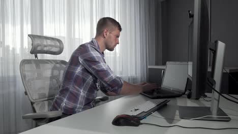 Handsome-IT-office-worker-using-two-computers-working-on-a-project